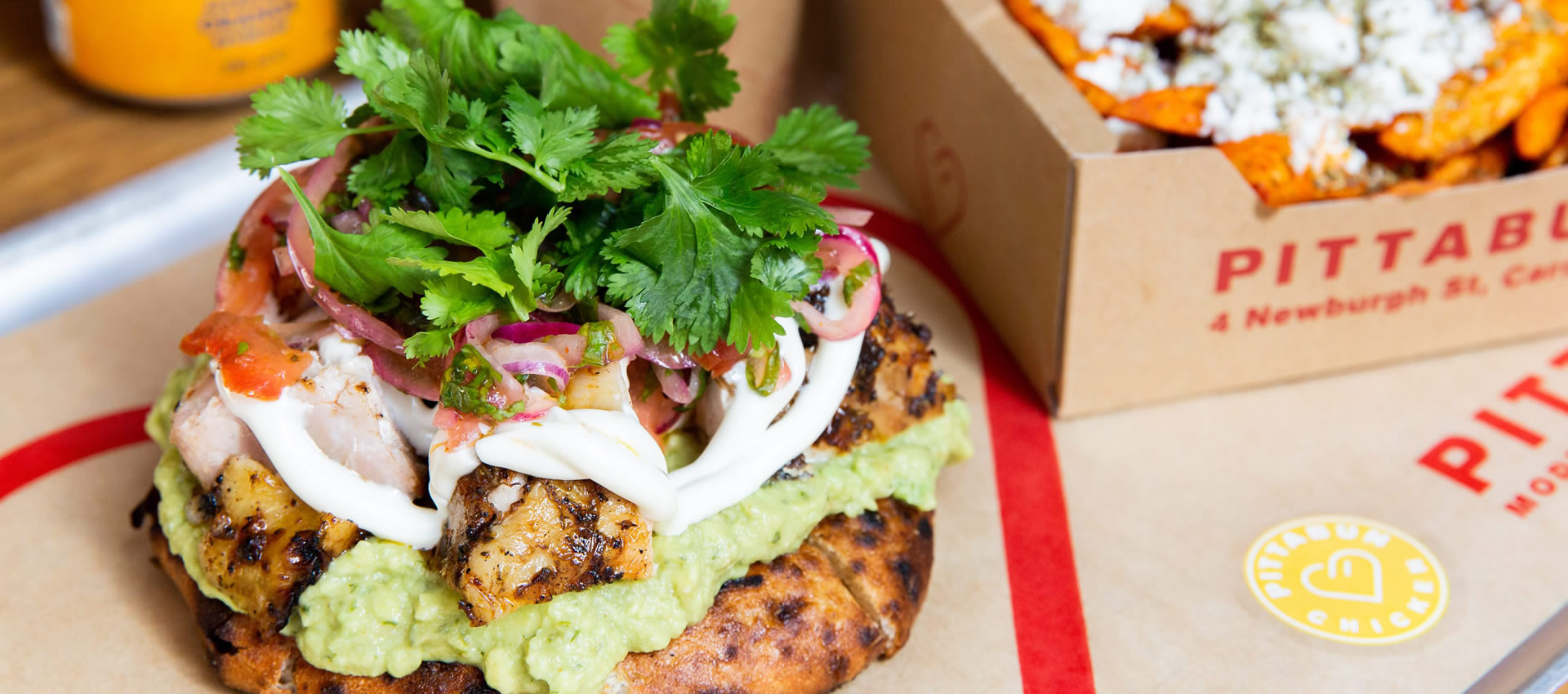 A close-up shot of our spicy chicken PITTABUN, served with chips on the side when you order as a combo