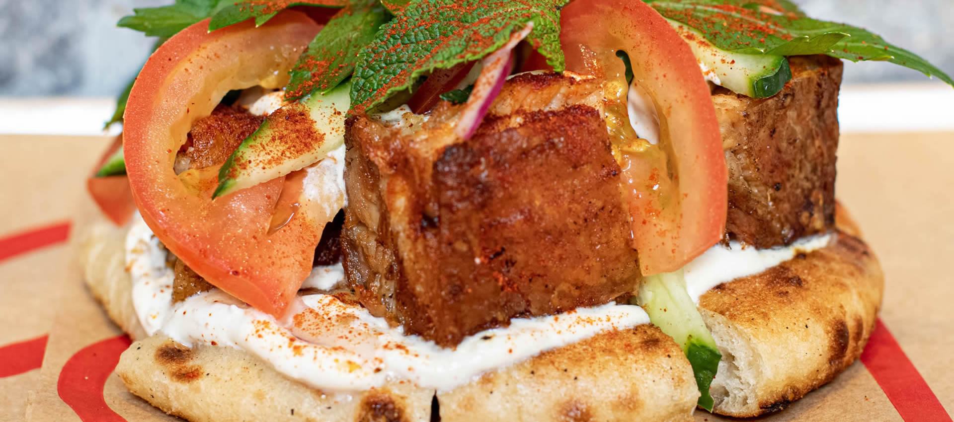 The filling of our souvlaki bun with pork belly, tzatziki, tomatoes, red onion, mint and parsley